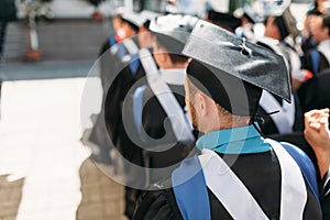 Successful graduates in academic dresses, at graduation, sitting