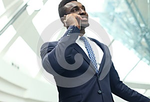 Successful handsome african american businessman talking on mobile phone in modern office.