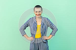 Successful handsome beautiful short hair young stylish woman in casual striped suit standing with hands on waist and looking at