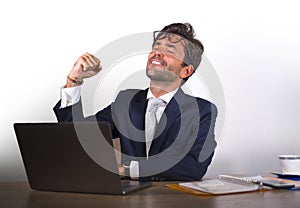 Successful handsome businessman in suit working at office computer desk celebrating financial success winning money smiling cheerf