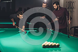 successful handsome man playing in pool at bar