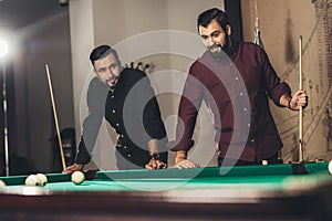 successful handsome men playing in pool