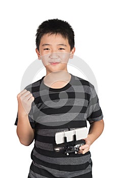 Successful happy Asian boy holding radio remote control for drone or helicopter and punching the air with his fist, isolated on w