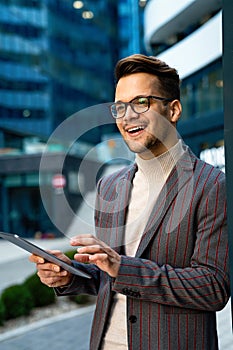Successful happy business man working on digital tablet in urban background