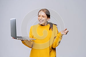 Successful happy shocked young woman with closed eyes holding laptop computer