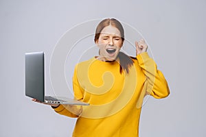 Successful happy shocked young woman with closed eyes holding laptop computer