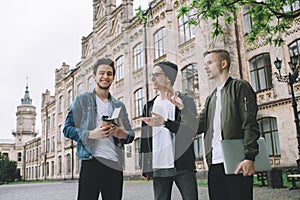 Successful happy students standing near campus or university outside