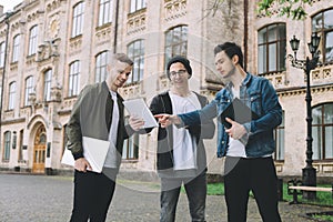 Successful happy students standing near campus or university outside