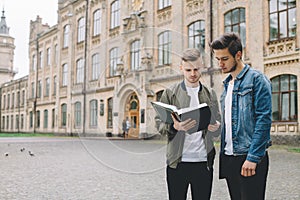 Successful happy students standing near campus or university outside