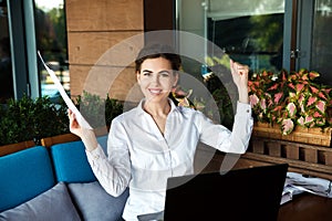 Successful happy young woman working on laptop in cafe outdoor