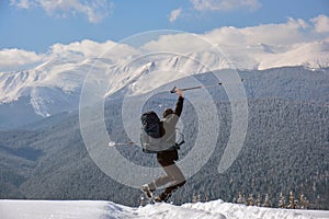 Successful hiker with backpack walking on snowy mountain hillside on cold winter day