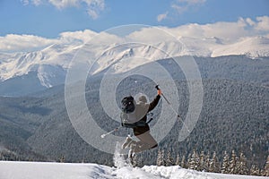 Successful hiker with backpack walking on snowy mountain hillside on cold winter day