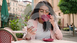 Successful Indian Arabian woman ethnic female girl businesswoman looking mobile phone drinking cup coffee morning