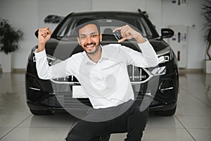 Successful indian businessman in a car dealership - sale of vehicles to customers.