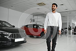 Successful indian businessman in a car dealership - sale of vehicles to customers.