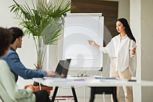Successful Japanese Businesswoman Presenting Project Pointing At Whiteboard In Office