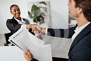 Successful job interview. Hired female candidate shaking hands with the HR team recruiter, signing employment contract