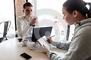 Successful leader and business owner leads an informal business meeting in a cafe.Young woman takes notes on a notepad photo