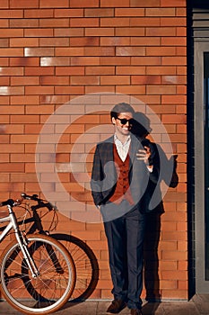 Successful male manager using smartphone near bicycle