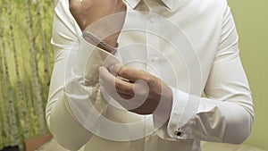 Successful man in the blue suit straightens his sleeves, close-up.