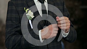 Successful man in brown checkered suit straightens his sleeves, close-up.