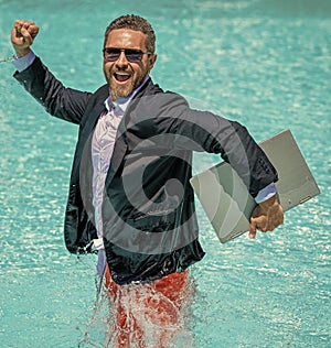 successful man. Businessman in suit with laptop in swimming pool. business man on summer vacation. businessman in wet
