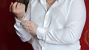 A successful man fastens buttons on his shirt, close-up.