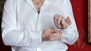 A successful man fastens buttons on his shirt, close-up.