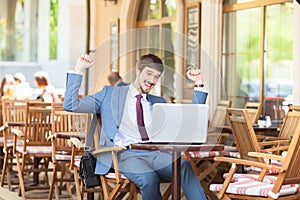 Successful man hands up outdoor at cafe