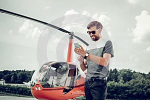 Prosperous successful man texting his wife after flight in helicopter photo