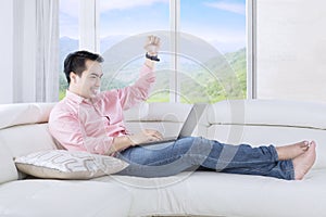 Successful man raising hand on sofa