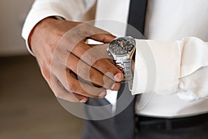 Successful man with white shirt and necktie looks on watch