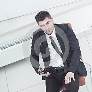 Successful Manager with a smartphone sitting in an office chair in the spacious office