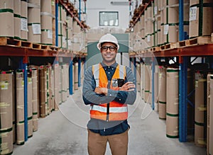 Successful manufacturing unit worker standing in warehouse distribution centre with folded hands with helmet and uniform