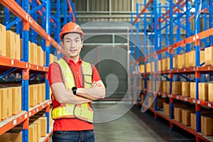 Successful manufacturing unit worker standing in warehouse distribution centre with folded hands with helmet and uniform smiling