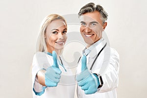 Successful medical team. Portrait of two happy male and female doctors in medical uniform and blue sterile gloves