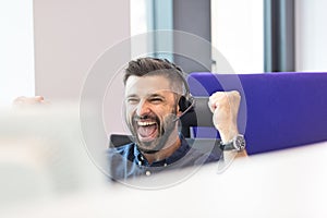 Successful mid adult businessman wearing headset while clenching fists in office photo