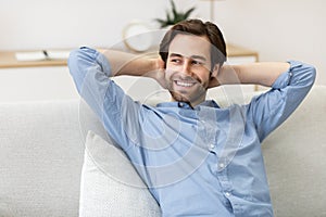 Successful Millennial Guy Resting On Sofa Enjoying Homey Weekend Indoor