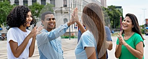 Successful multiethnic team of young adults give high five to friend