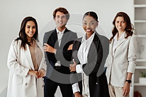 Successful multiracial business team with black female leader standing in office and smiling at camera