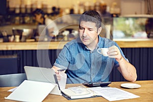 Successful new small business restaurant owner calculating bills taxes and expenses of his small business photo