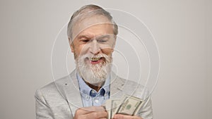 Successful old man having money in studio. Smiling guy counting dollars indoors.