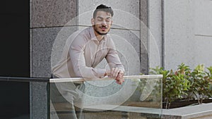 Successful pensive bearded business man professional specialist guy boss goes out to balcony terrace in office building