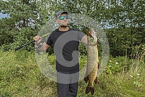 Successful pike fishing. Happy fisherman hold muskie fish