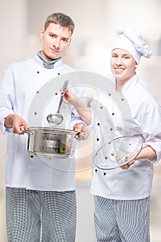 successful professional chefs with a pan and a ladle in a commercial
