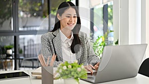 Successful Asian businesswoman typing on laptop keyboard, working in her office
