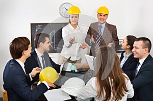 Successful professionals with laptops and helmets having working