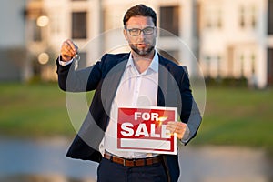 Successful real estate agent in suit with sign for sale. Real estate broker front of new house. Real estate home owner