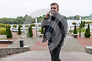 successful satisfied businessman speaks with a smile on a mobile phone well in a business suit on the background of a