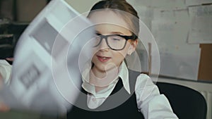 Successful schoolgirl willingly works with pc and papers in office 4K